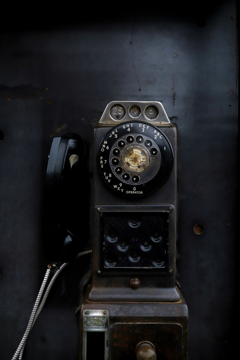An old rotary payphone with coin slots for quarters, dimes, and nickels.