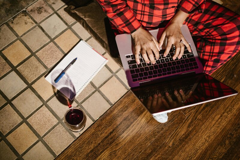 Writing Pajamas Website Copywriting (image shows a girl in strip pajamas sitting on the flour holding her laptop)