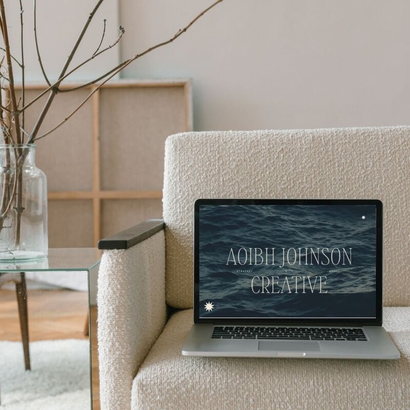 laptop on a white boucle chair with a website home page design