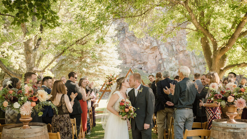 Couple shares a kiss at the end of the aisle after their outdoor wedding ceremony