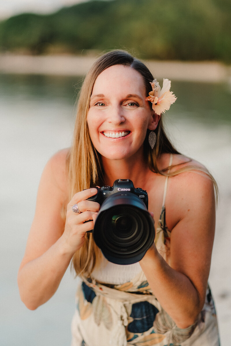 Laura Pittman holding a camera on a beach in Hawaii