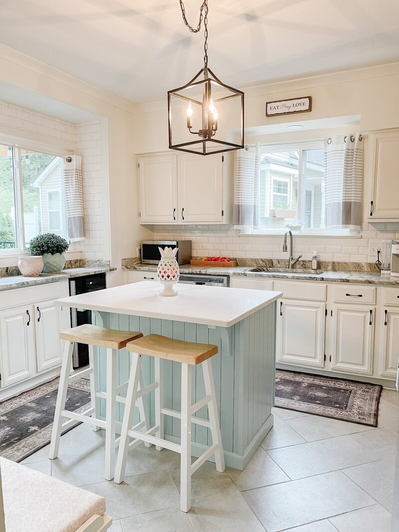 Brightly lite white kitchen with a light blue island.