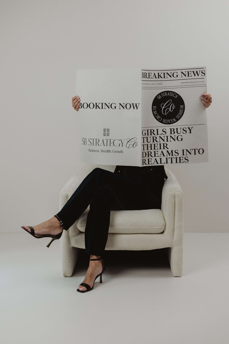 A women in black pants and stool opening a newspaper about turning dreams into reality.