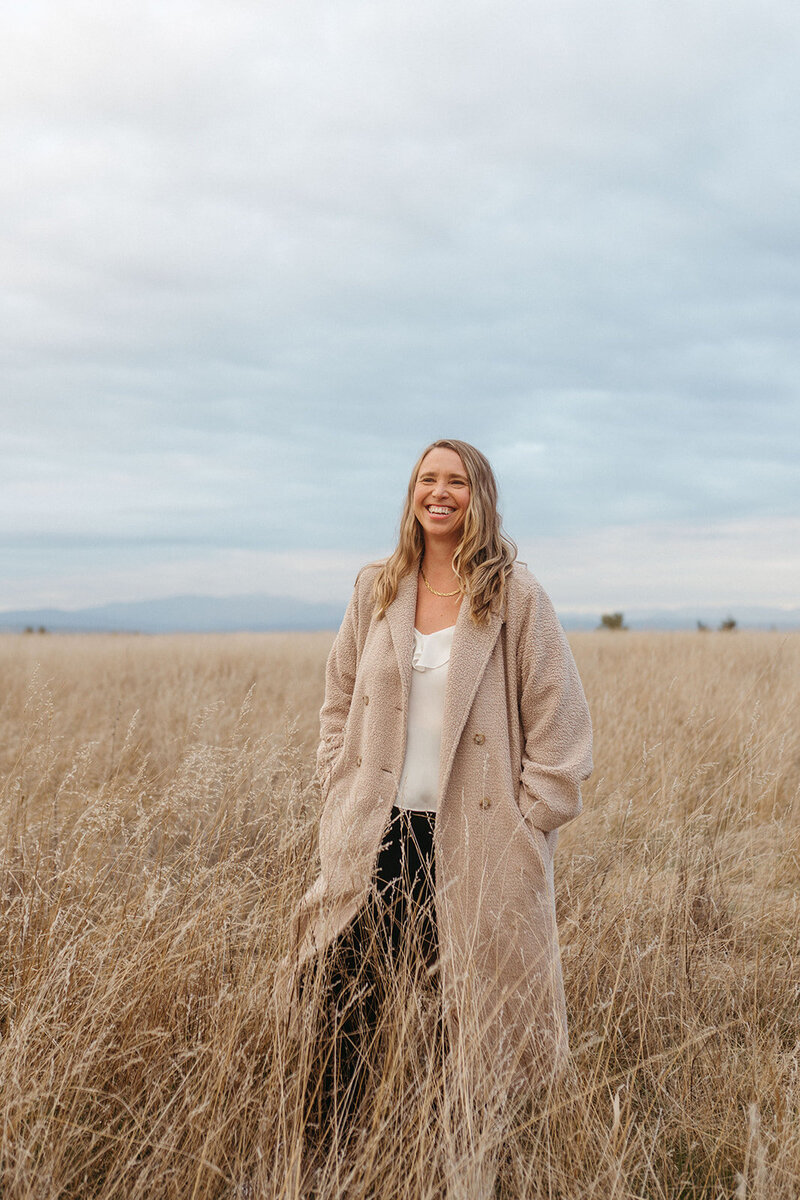 A person leaning against a wall drinking from a glass bottle 