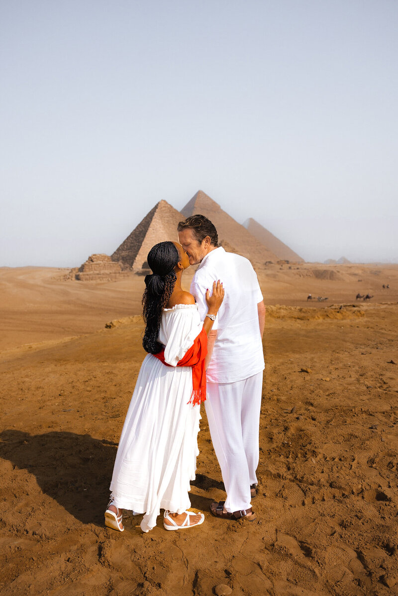 Couple embraces in front of pyramids