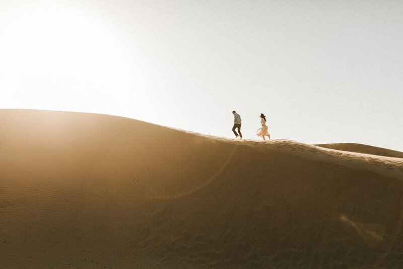 couple running through sand dunes