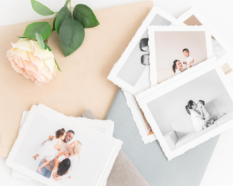 5x7 deckled edge rag prints scattered atop albums with a flower accent