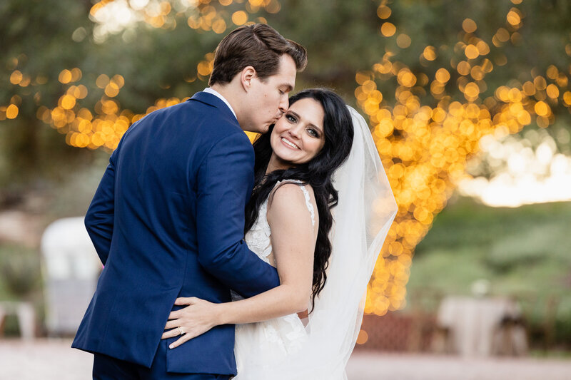 A bride and groom kissing at sunset