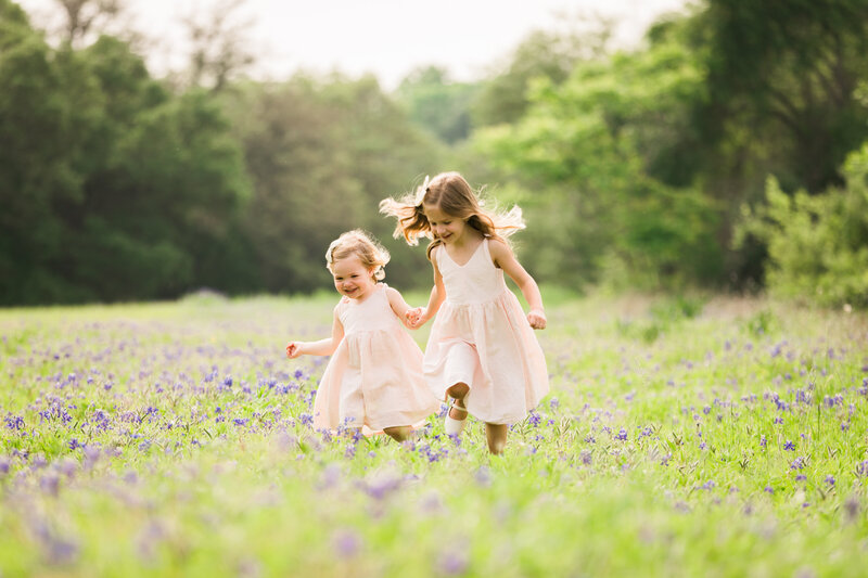 Sisters holding hand running through field of bluebonnets, Austin Family Photographer