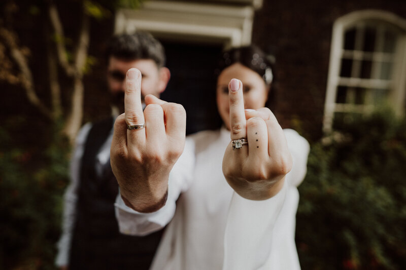 bride and groom with their wedding fingers up