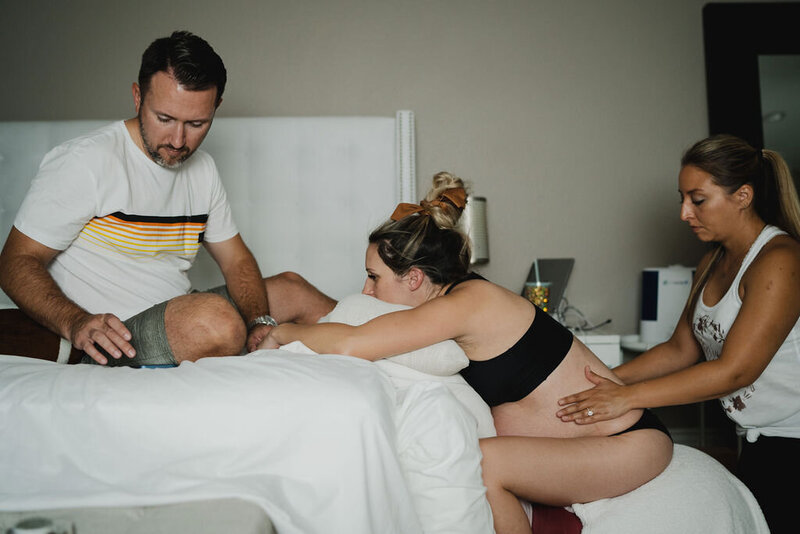 Postpartum doula holding new born baby for new mother to take a rest