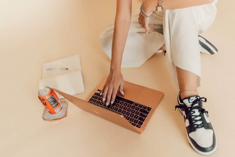 Close up of woman sitting on ground with laptop and coke