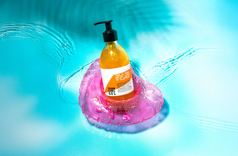 Photo du gel coiffant Cut By Fred posé sur une base rose flottant dans l’eau bleue, Studio Helloday.