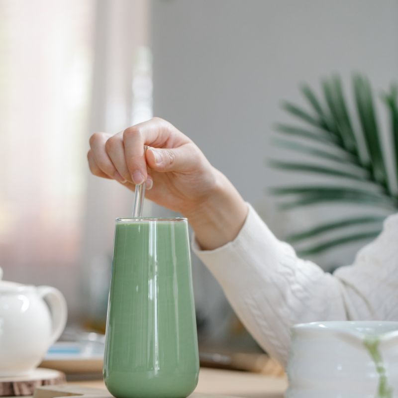 Woman stirring a mint Chocolate Chip Smoothie in a glass.
