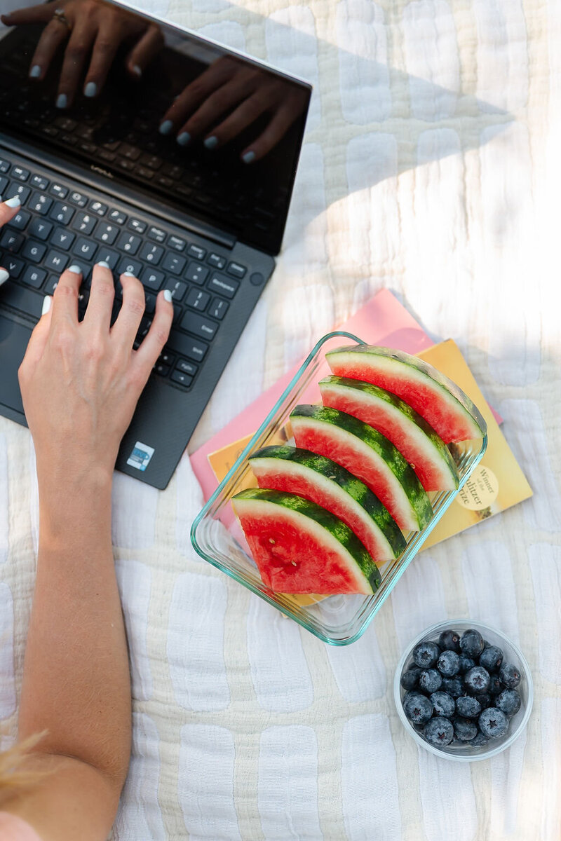 Flat lay of a person working on a computer on a picnic blanket