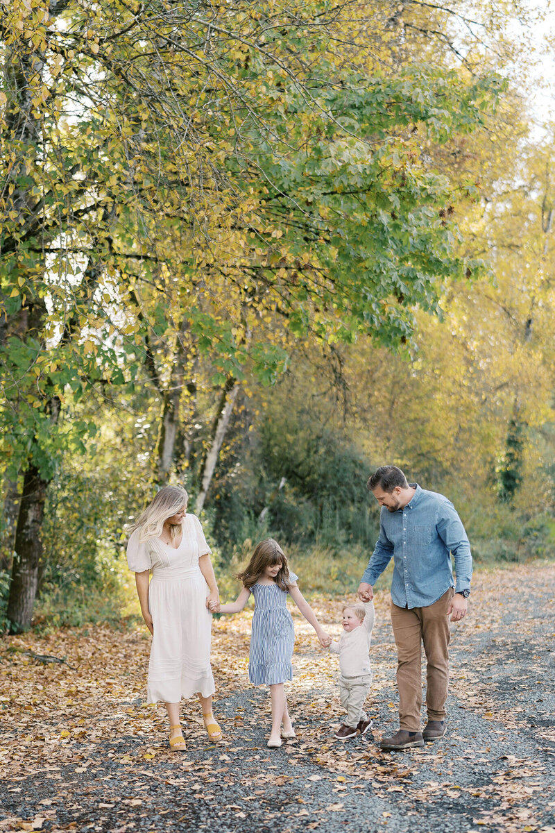 family walks through fall leaves in a blog post about everything to know about fall family photography