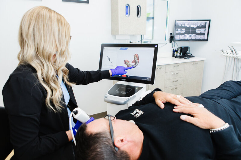 Prosthodontist explaining clear aligner treatment to a patient at Peak Prosthodontics in Lethbridge—offering a discreet, effective option for straight teeth.