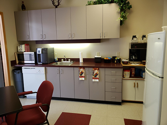 Kitchen photo at execuserv plus inc that shows the dishwasher, microwave, coffee maker, sink, fridge and seating.