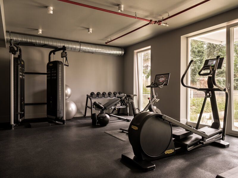 Vielseitige Ausstattung im Fitnessraum des Hotels the breeze mit Fahrrad, Laufband, Stepper, Gewichten und Kabelturm.