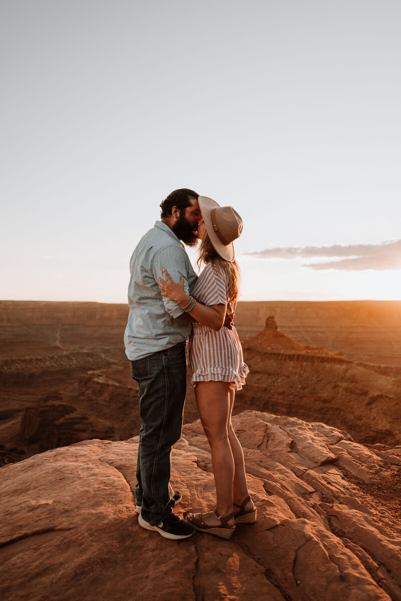 Engaged couple sharing a kiss near the edge of a cliff at Dead Horse Point State Park