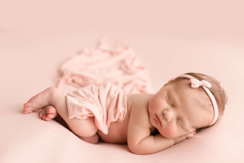Baby girl on pink backdrop in Seattle studio with pink bow