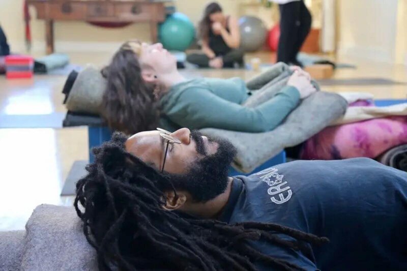 Students in supta baddha konasana during hatha yoga teacher training California