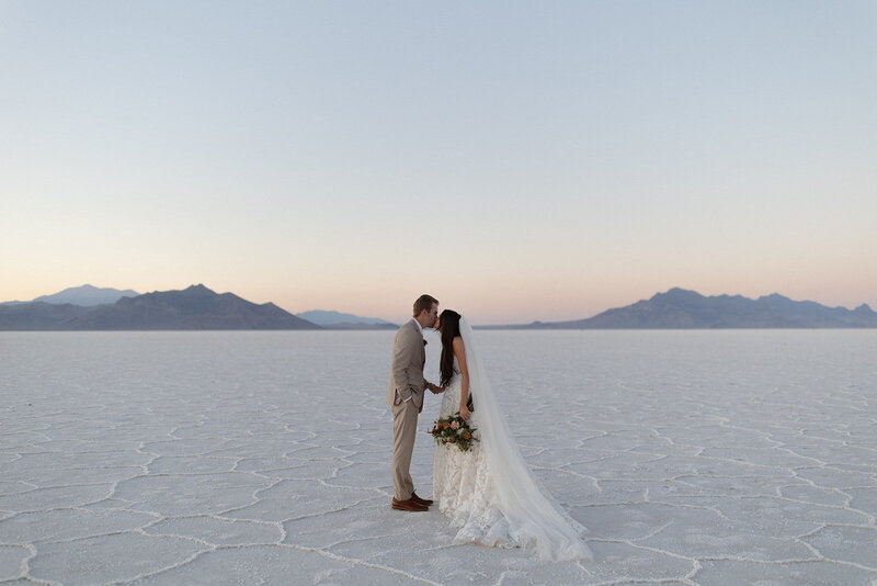 Bride and groom kissing at Bonneville Salt Flats in Utah, captured at sunset by a wedding and elopement photographer.
