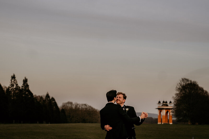 Grooms in field at sunset