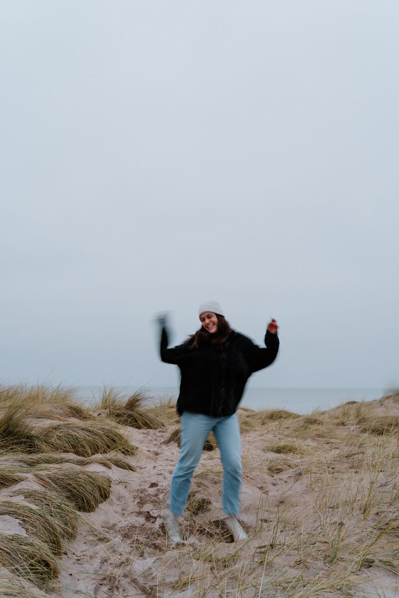 Joyful photo of Kansas City wedding and family photographer dancing on the coast of England.