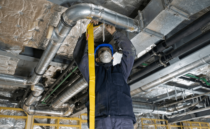 Vigor Mechanical technician installing HVAC ductwork in a commercial ceiling during new construction
