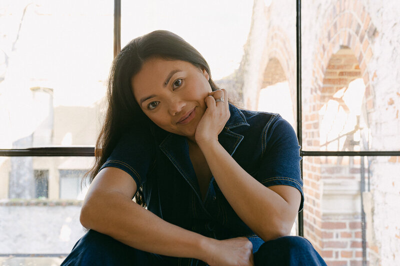 Female photographer sitting, smiling and resting hand on face