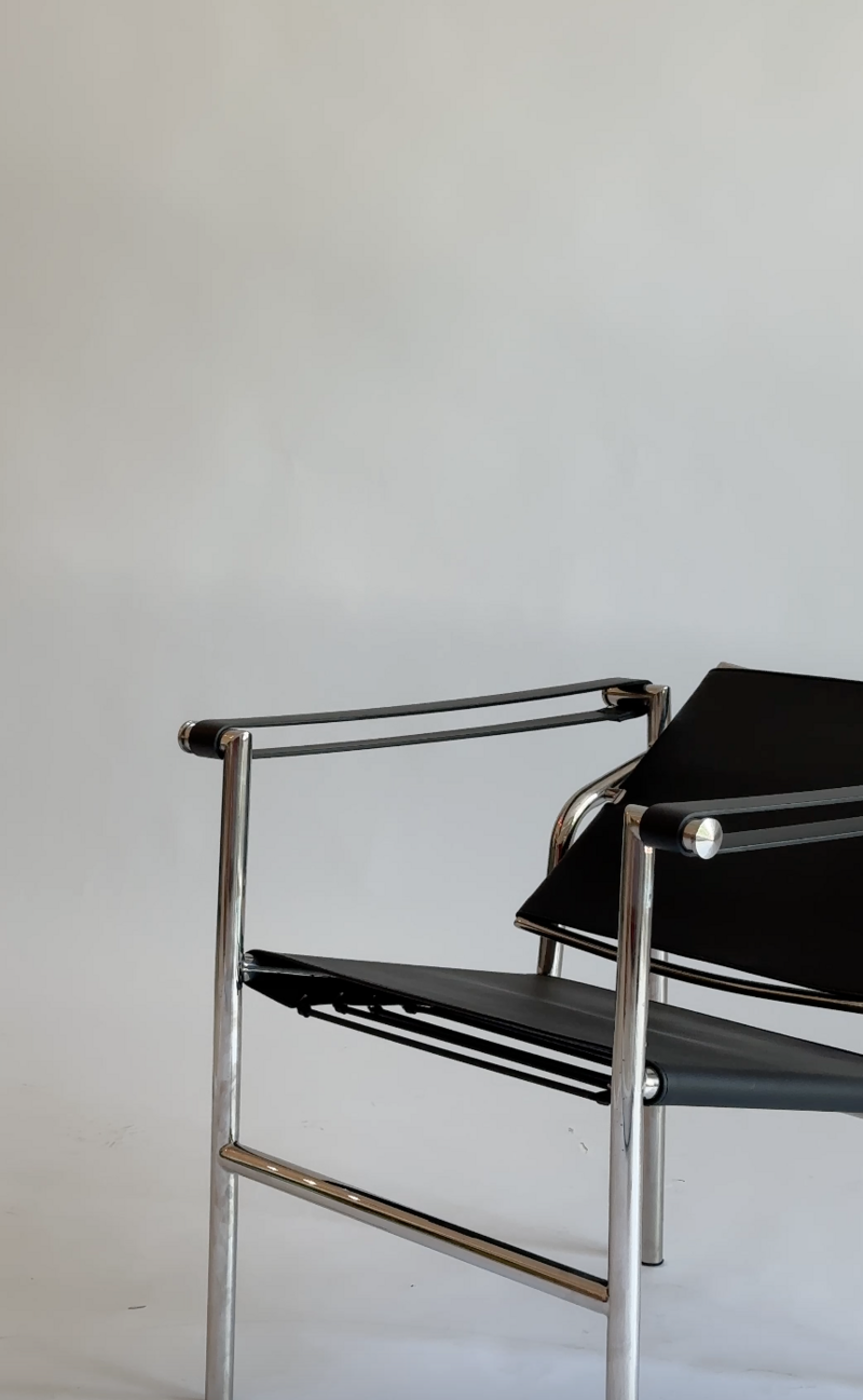 Modern black chair with silver arm rests on a clean photography backdrop