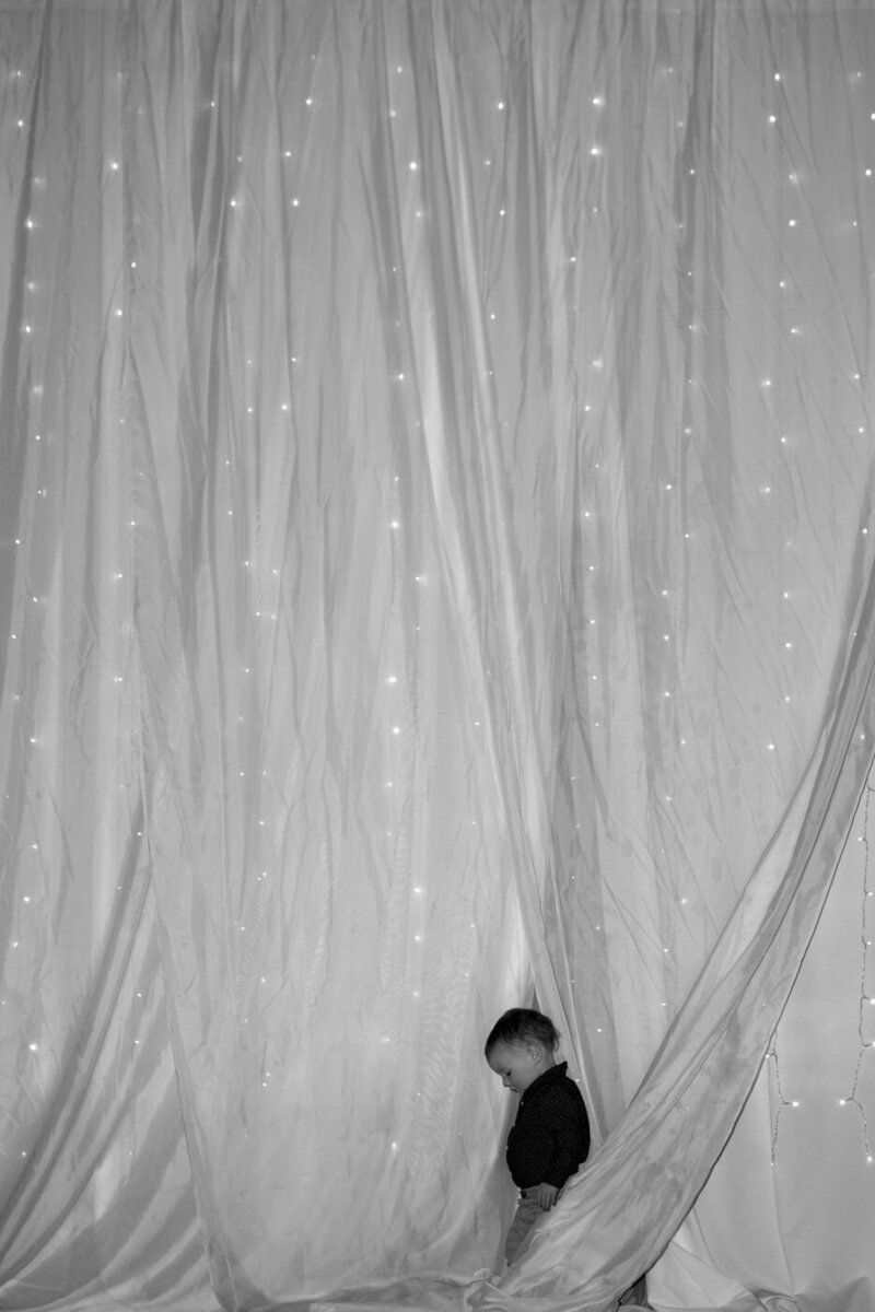 A small child walks amongst drapery at a wedding venue.