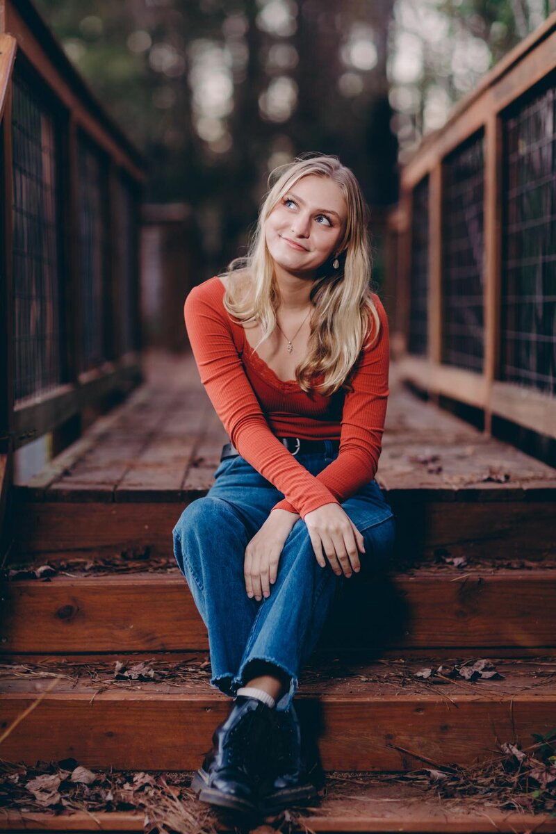 Senior portrait of a girl sitting on a crosswalk with a thoughtful look while she is contemplating her next big move.