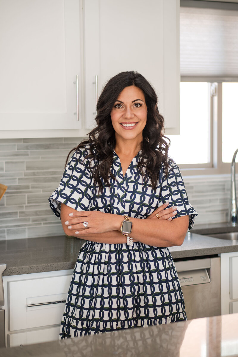 Female entrepreneur with dark hair holding books and smiling