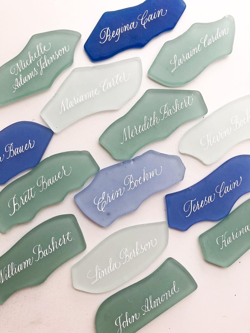 rows of lined up sea glass place cards written in calligraphy