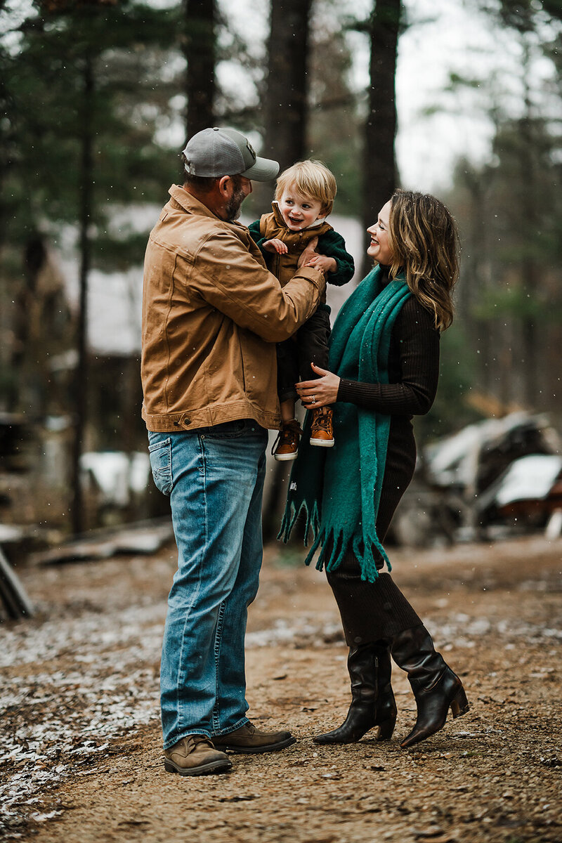 Small family of three standing standing in the fresh falling snow.