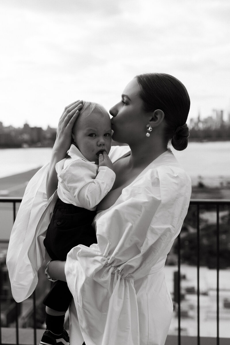Classic and timeless bride holding her son at her city wedding on rooftop