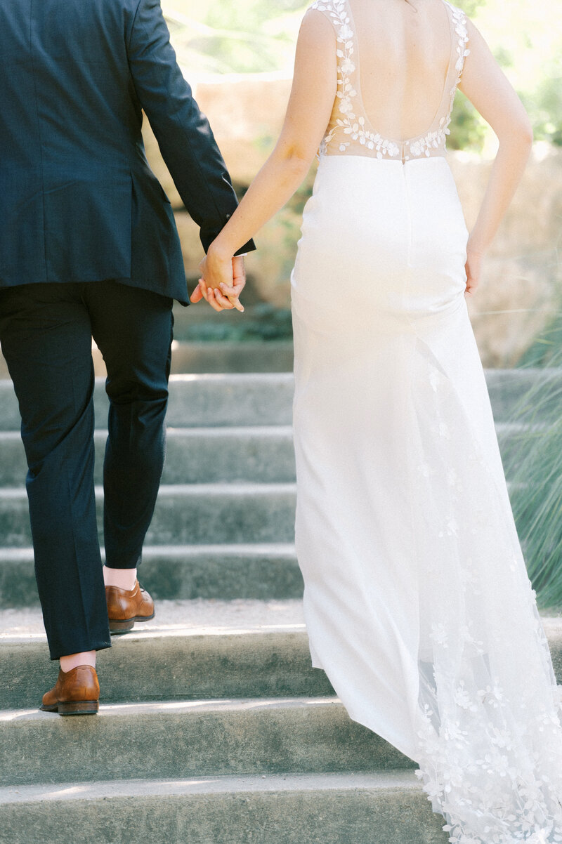 bride and groom walking up stairs in garden at ladybird johnson wildflower center by austin wedding photographer tara paige weddings
