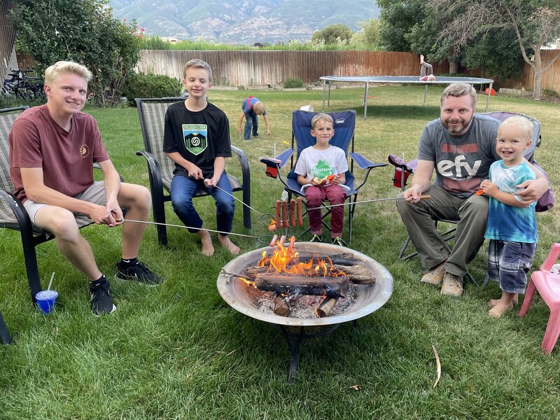 The owners of Cornerstone and their kids sitting around a firepit in their backyard