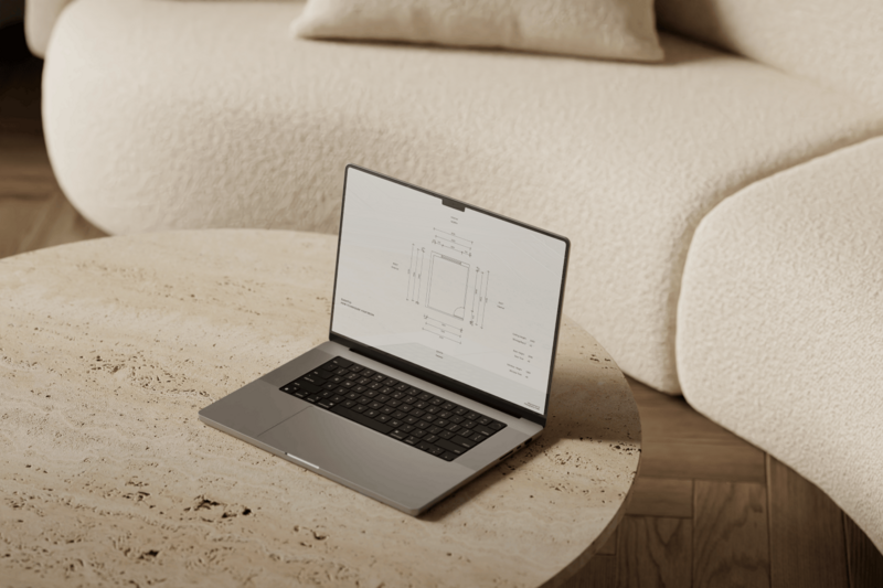 An open laptop rests on a round travertine coffee table, displaying instructions on measuring a room and drawing a floor plan. In the background, a curved boucle sofa adds a sense of softness and organic form to the space.