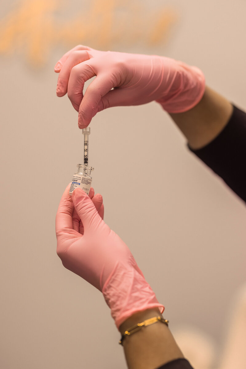 person holding needle inserted into botox bottle