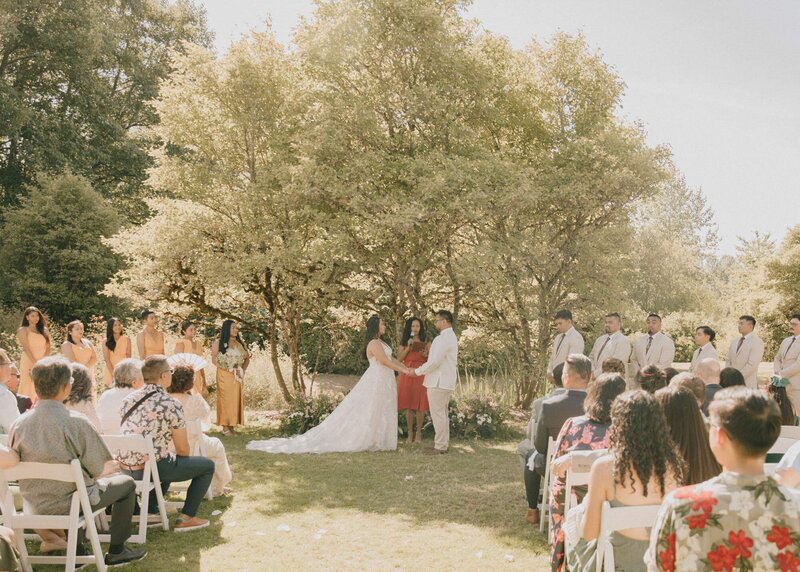 couple standing under large tree during wedding ceremony