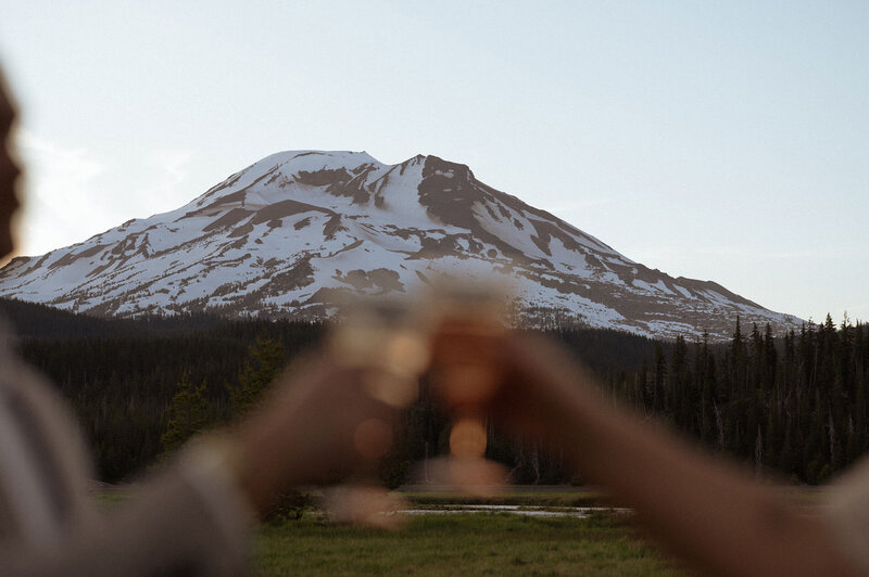 intimate elopement celebration with couple toasting champagne in front of Mt. Bachelor in Central Oregon
