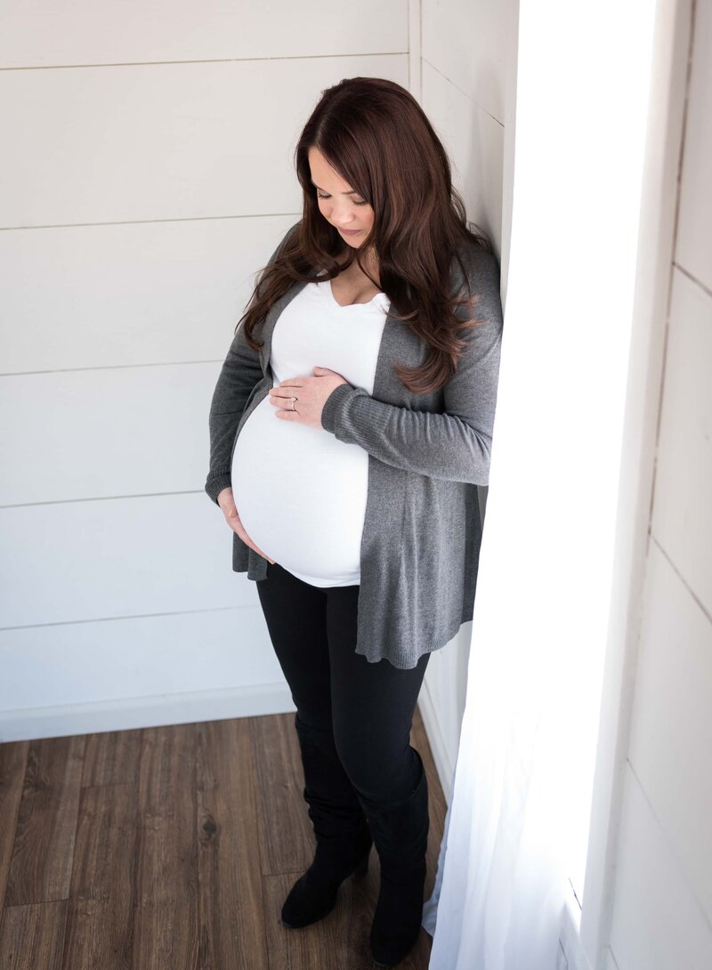 Expectant Mother Standing by Window Holding Baby Bump