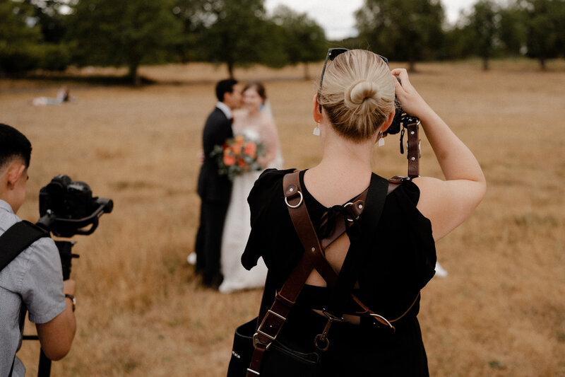Photographer taking a photo of a wedding couple in an open field