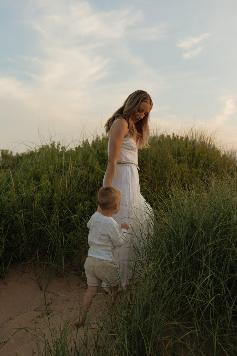 mom and son walking through beach grass for lifestyle photos in pei