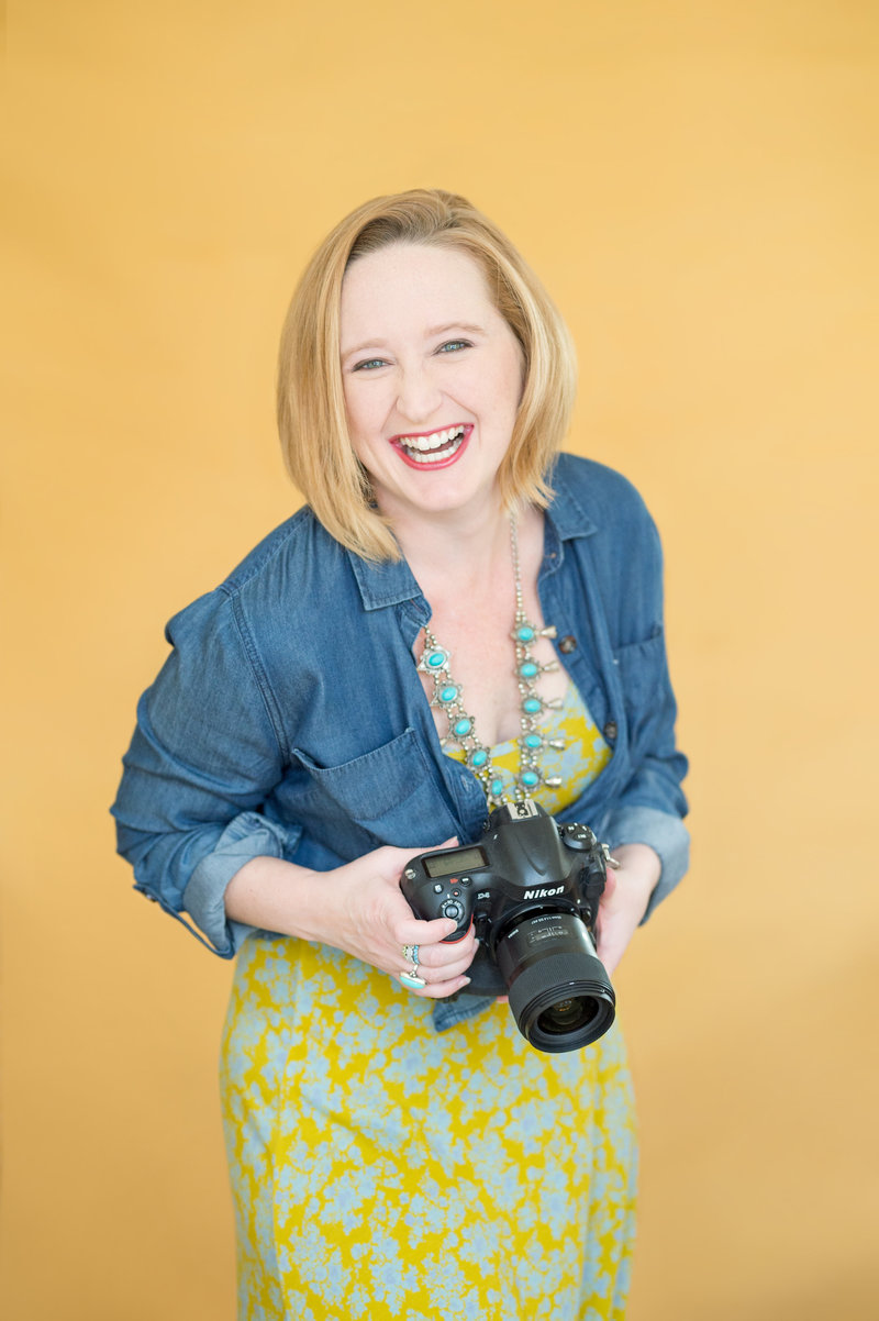photographer with a yellow background holding a camera