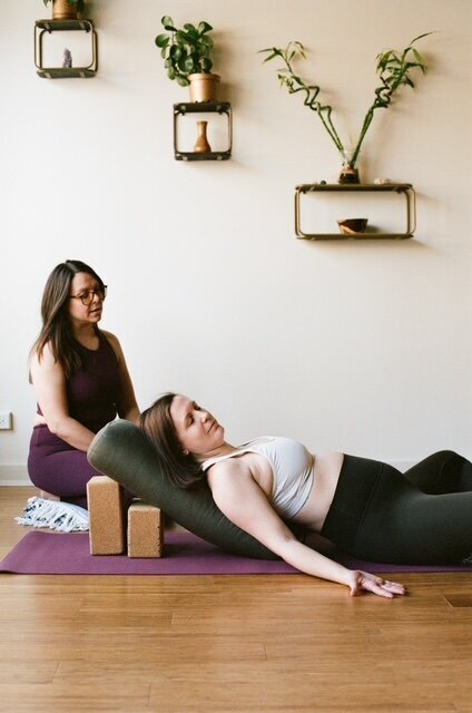 Two women practicing yoga on a mat, demonstrating various poses in a serene indoor environment.