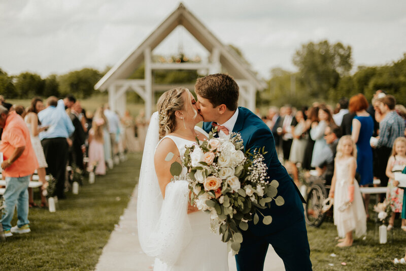 bride and groom kissing at the end of the aisl